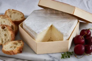 Dauphin soft cheese in a wooden box with baguette and cherries - Dauphin | KnowTheCheese