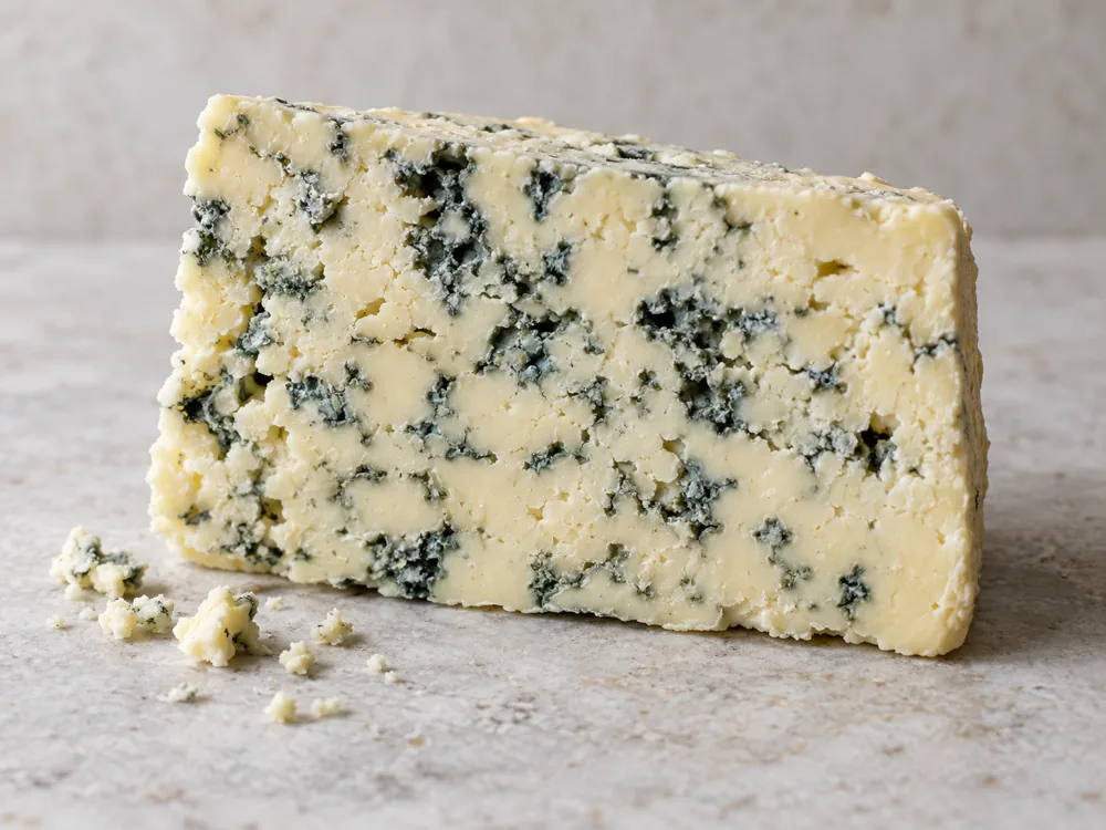 Pale crumbly blue-veined cheese cut face with small crumbs - Devon Blue | KnowTheCheese