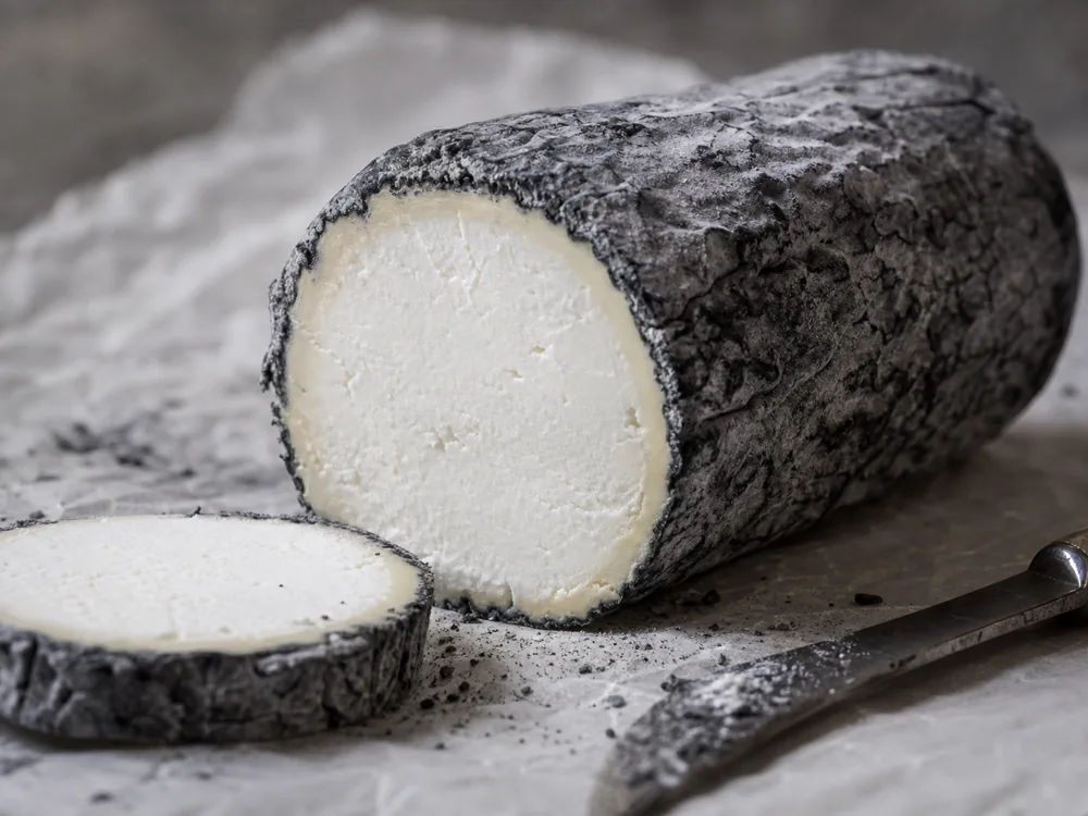 Driftwood ash coated goat cheese close cut with gray rind and white paste - Driftwood | KnowTheCheese