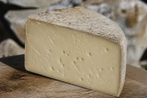 Wedge of Dura cheese with a rustic natural rind and pale straw-colored paste - Dura cheese | KnowTheCheese