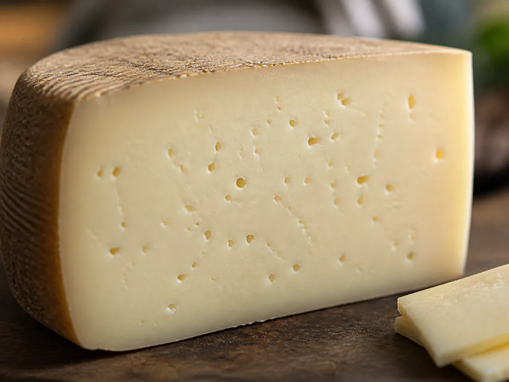 Close-up of the dense paste and scattered eyes in a cut wedge of Dura cheese - Dura cheese | KnowTheCheese