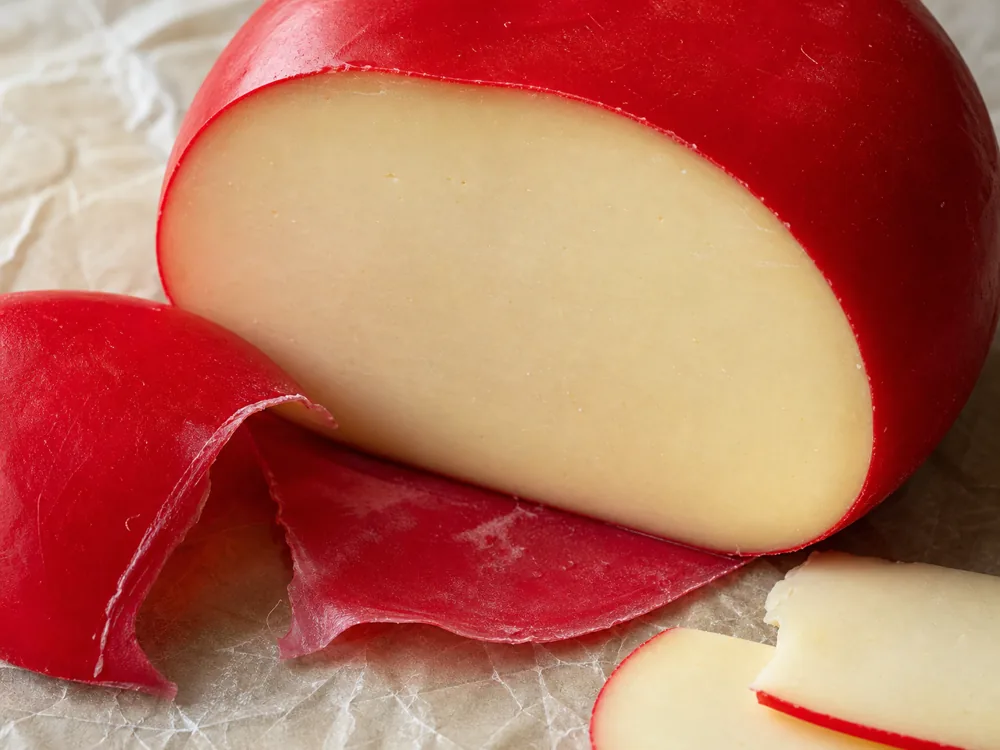Cut waxed Edam wheel showing smooth pale paste - Edam Cheese | KnowTheCheese