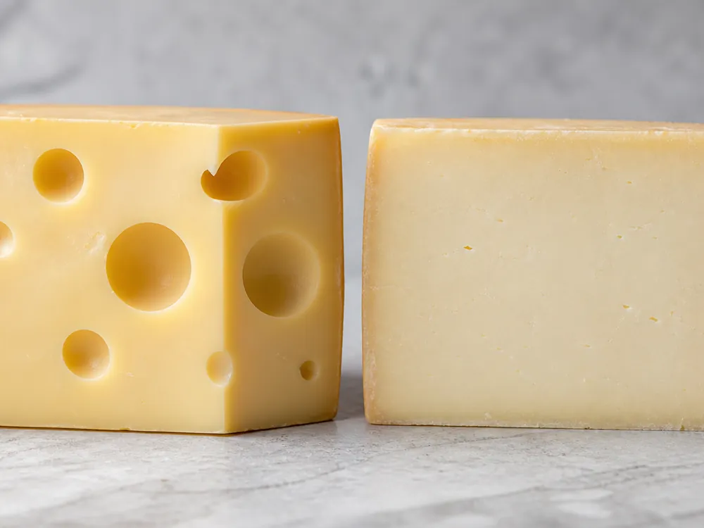 Large eyes in Emmental beside the closed paste of Gruyere - Emmental vs Gruyere | KnowTheCheese