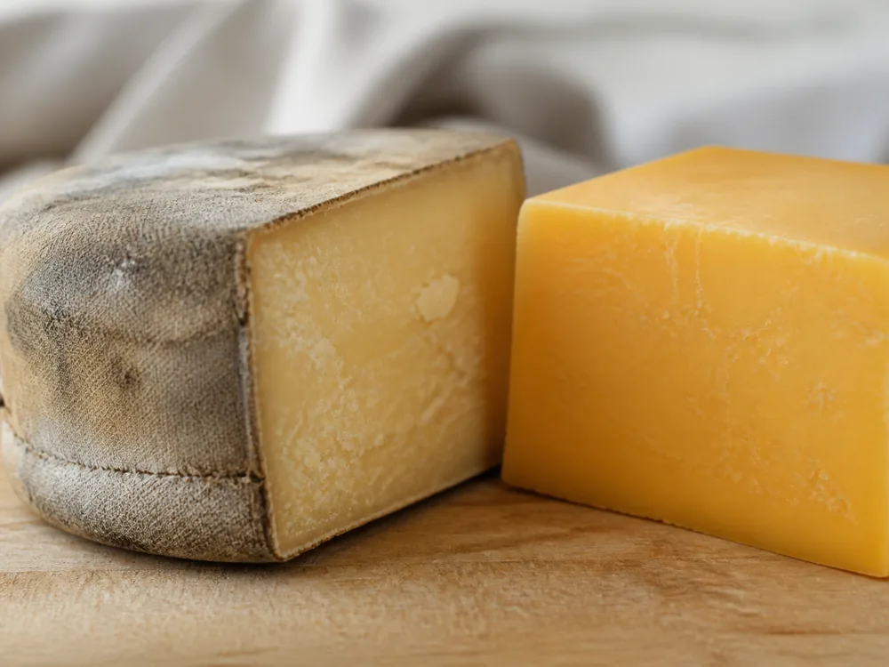 Clothbound Flagship Reserve wheel beside a rindless block of standard Flagship cheese - Flagship cheese | KnowTheCheese