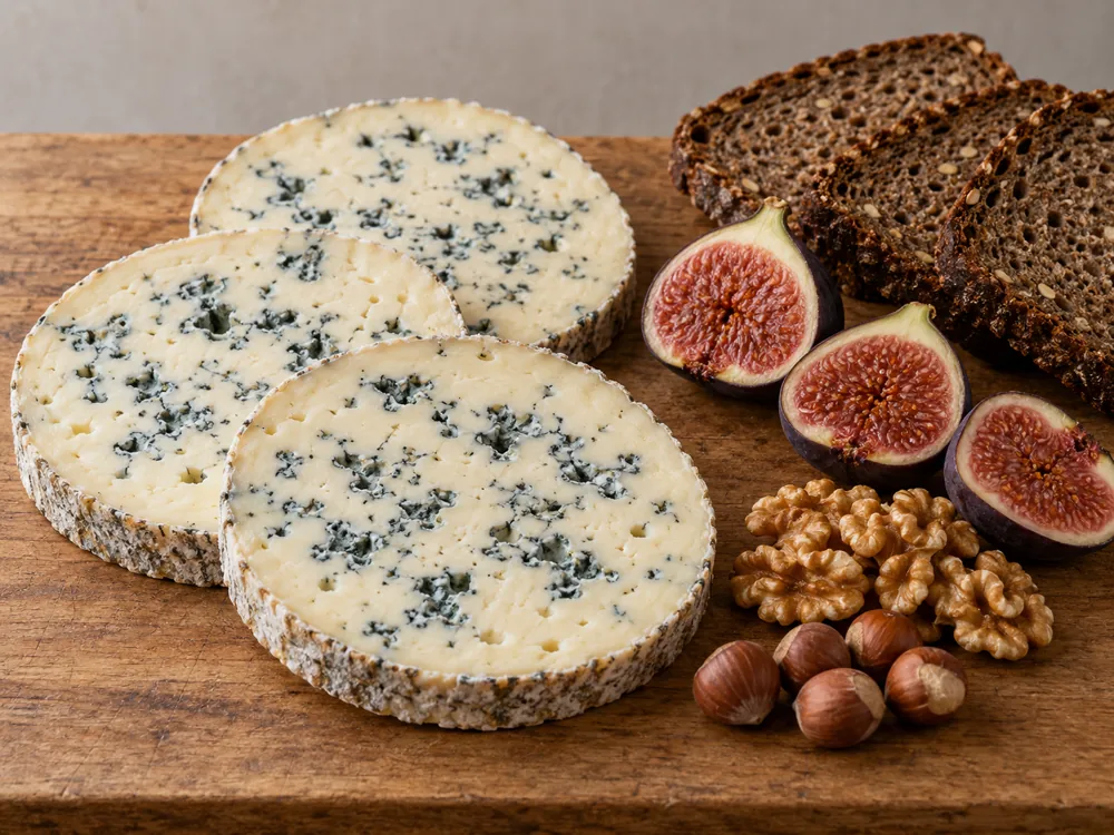 Round slices of Fourme d'Ambert with halved figs, walnuts, hazelnuts and rye bread - Fourme d'Ambert | KnowTheCheese