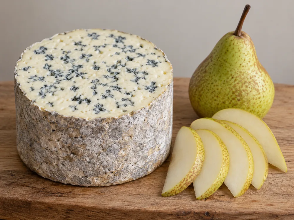Half a Fourme d'Ambert standing upright beside sliced pears on a wooden board - Fourme d'Ambert | KnowTheCheese