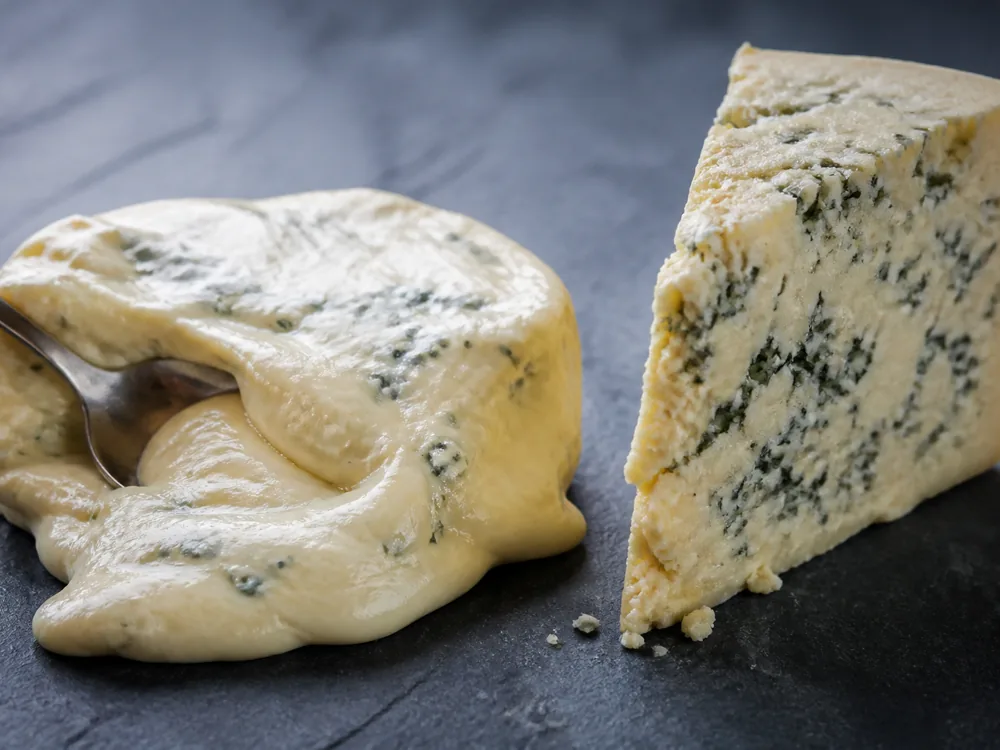 A soft spoonable blue cheese beside a firm crumbly one with denser veining - Gorgonzola | KnowTheCheese