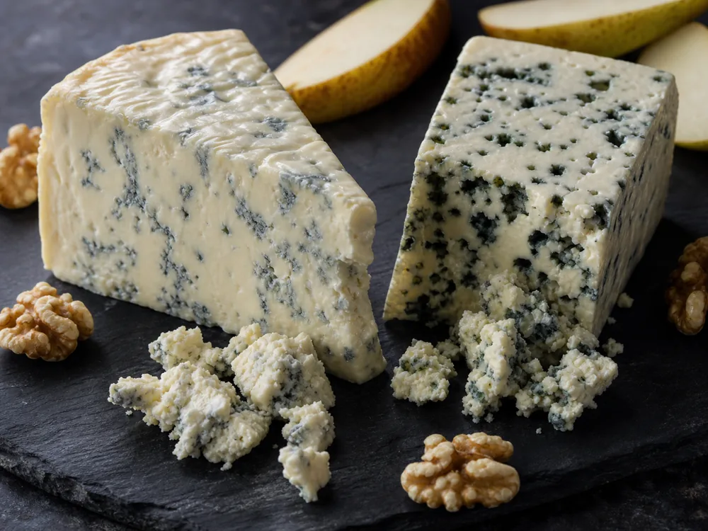 Two blue cheese wedges with different veining and crumble.