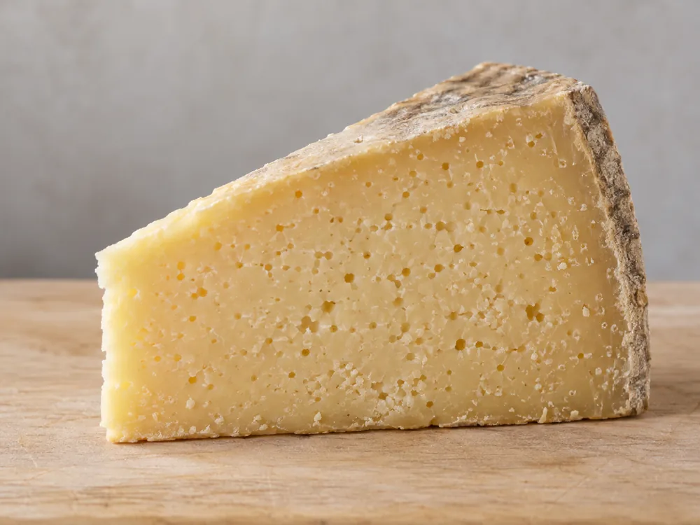 Wedge of Graviera with a compact straw-coloured paste full of small round holes - Graviera | KnowTheCheese