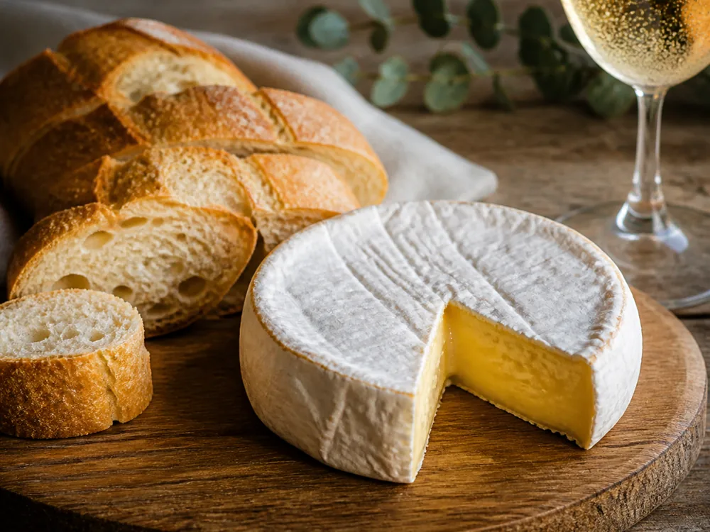 Whole wheel of Green Hill cheese served on a board with baguette - Green Hill cheese | KnowTheCheese