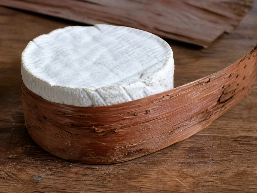 Spruce bark being wrapped around a wheel of Harbison cheese - Harbison cheese | KnowTheCheese