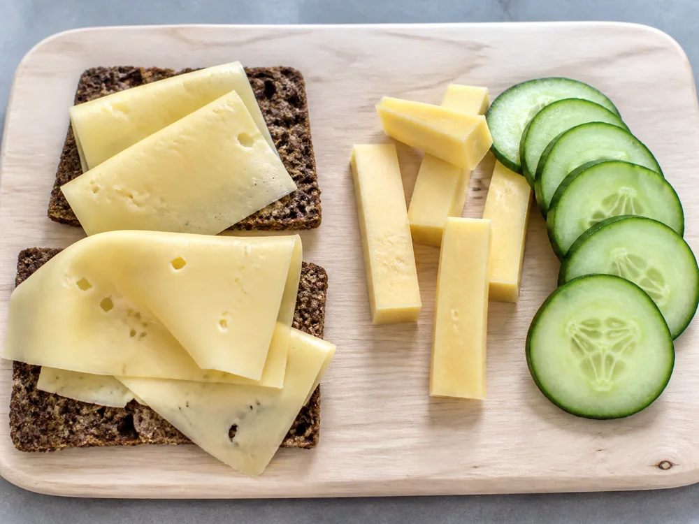 Thin Hushållsost slices on crispbread beside thicker snack pieces - Hushållsost cheese | KnowTheCheese