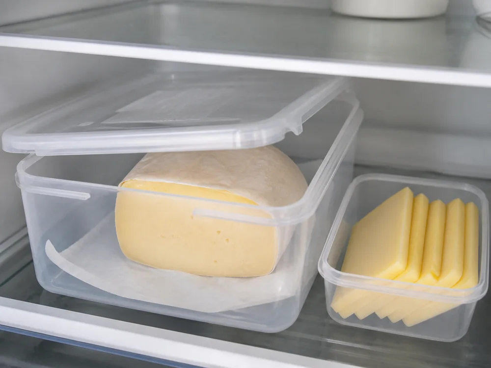 Cut Hushållsost wheel wrapped in paper inside a refrigerator box - Hushållsost cheese | KnowTheCheese