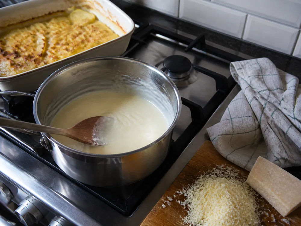 Pale farmhouse cheddar sauce stirred off the heat beside potato gratin - Isle of Mull cheese | KnowTheCheese