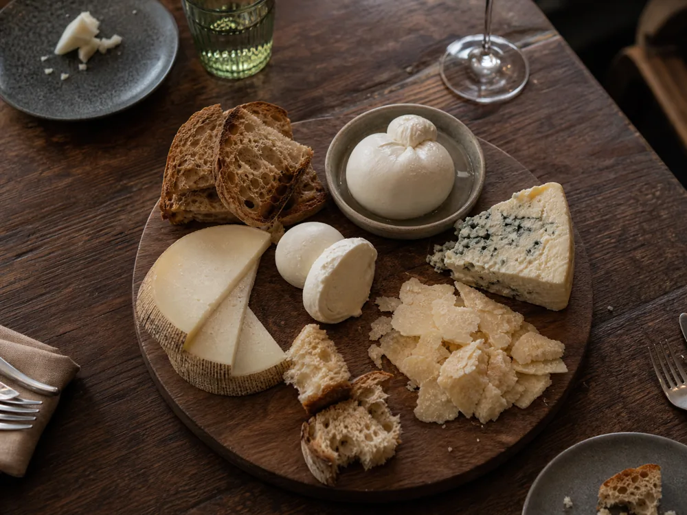 Italian cheese board with Parmigiano, mozzarella, burrata, Gorgonzola, Pecorino Toscano, and rustic bread