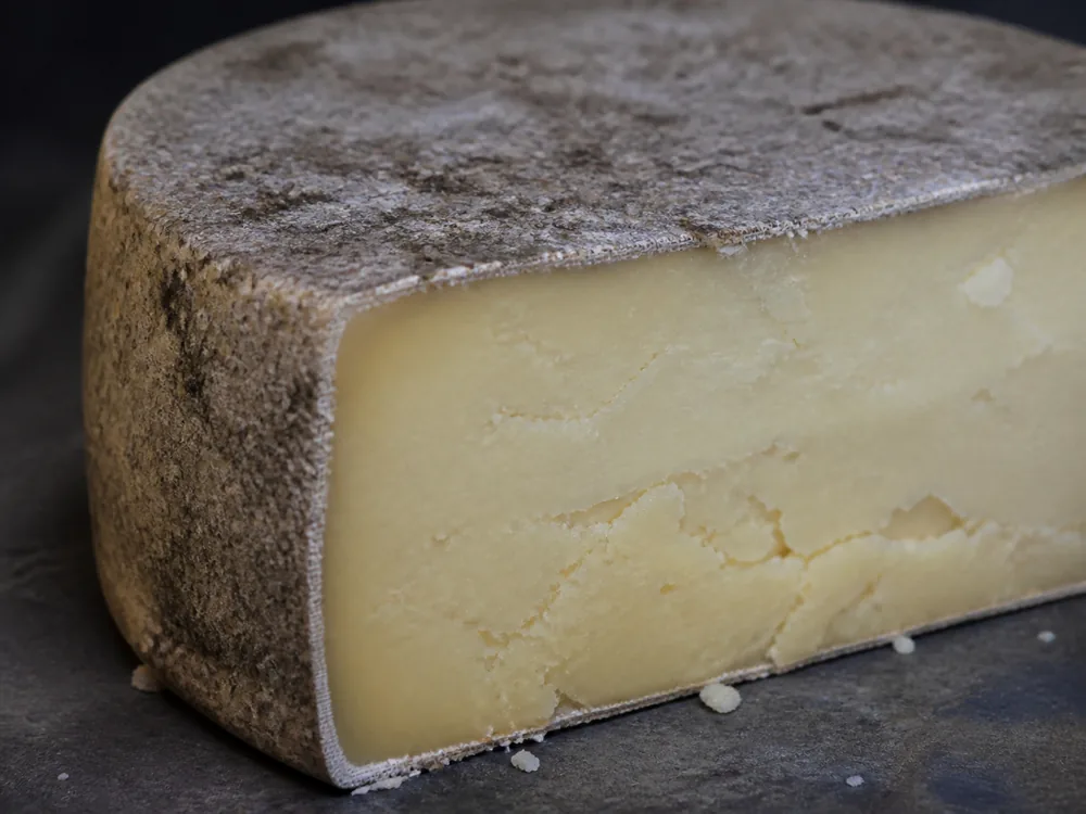 Muslin cloth visible beneath a mottled farmhouse Cheddar rind - Keen's Cheddar | KnowTheCheese