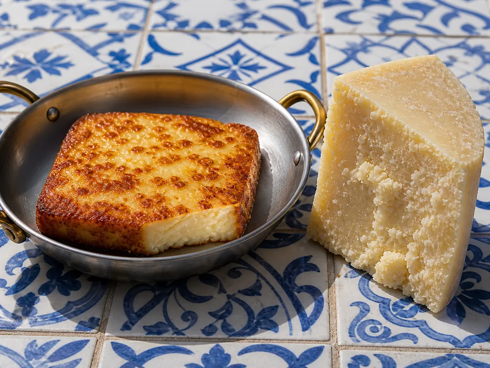 Younger Kefalotyri browned for saganaki beside an older brittle wedge - Kefalotyri | KnowTheCheese