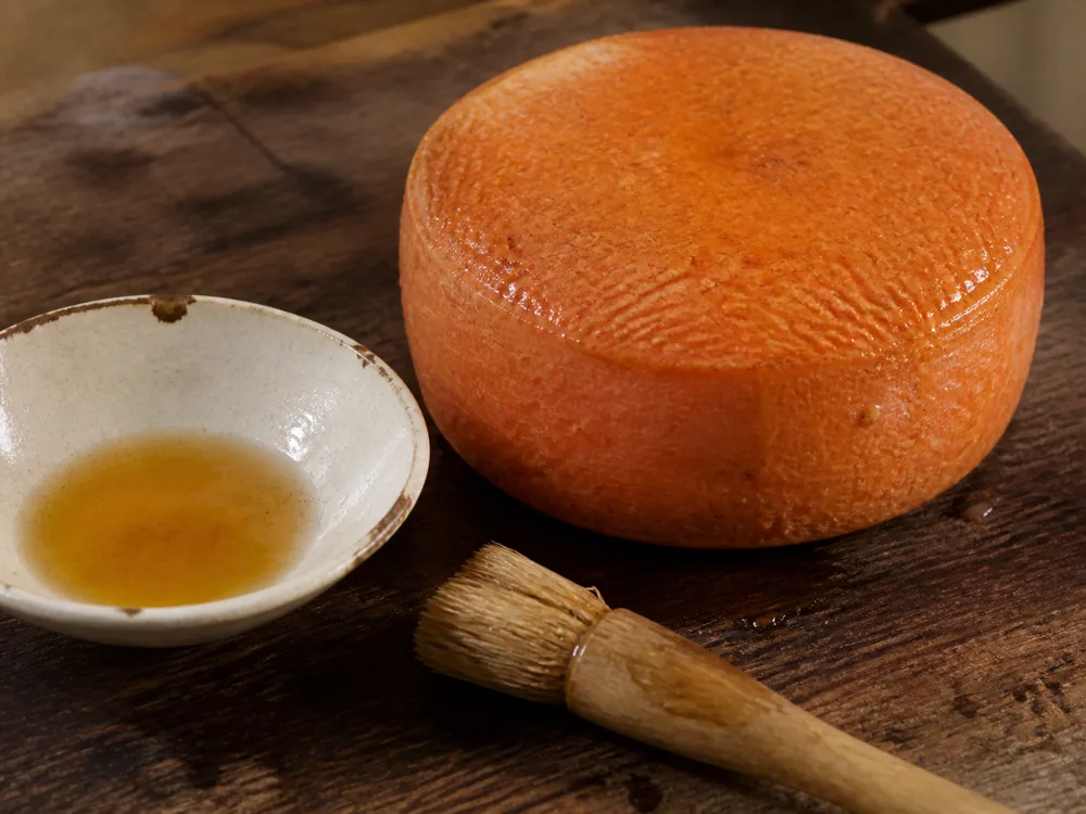 Cider-washed orange cheese rind beside a small wash bowl - Keltic Gold | KnowTheCheese