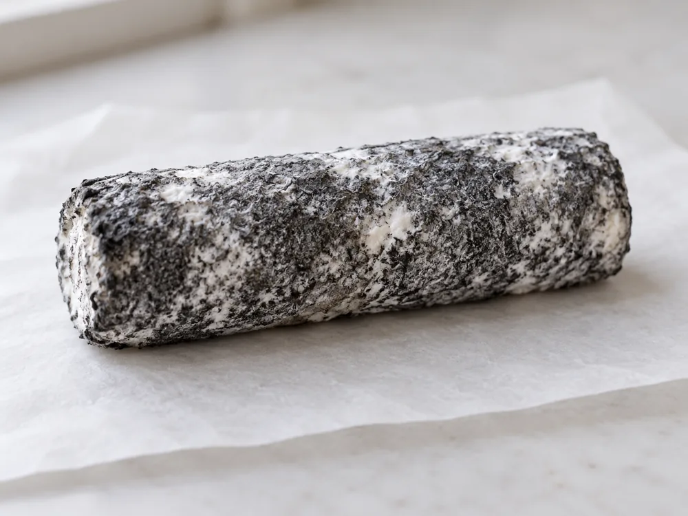 Goat cheese log with a grey ash coat speckled with white mould - Kidderton Ash | KnowTheCheese