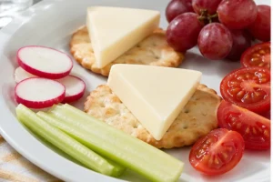 Processed cheese wedges with crackers radish celery tomato and grapes - La Vache Qui Rit | KnowTheCheese