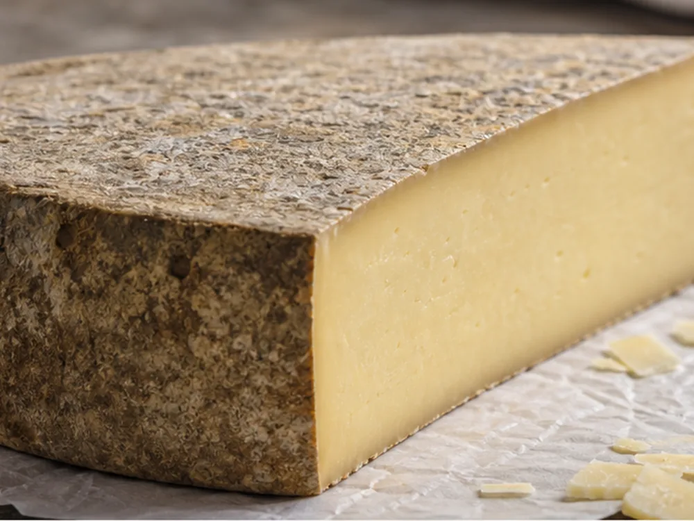 Close cut face of firm Laguiole style cheese with thick rind and shavings - Laguiole | KnowTheCheese