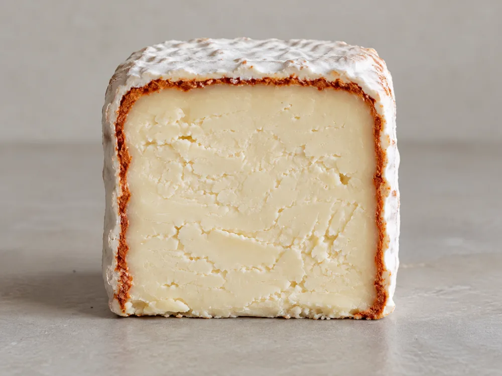 Cut brick of Leonora a Fuego with a rust-red paprika layer under the white rind - Leonora a Fuego | KnowTheCheese