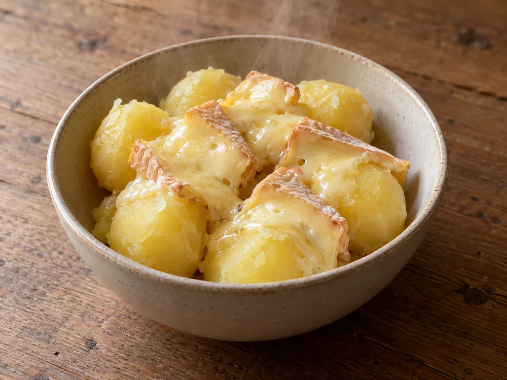 Pieces of Limburger softening on a bowl of hot boiled potatoes - Limburger Cheese | KnowTheCheese