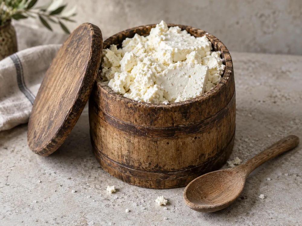 Crumbly white fresh cheese packed in a small wooden barrel with its lid beside it - Liptauer | KnowTheCheese