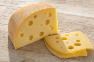 Wedge of Maasdam with smooth pale paste and large holes - Maasdam cheese | KnowTheCheese