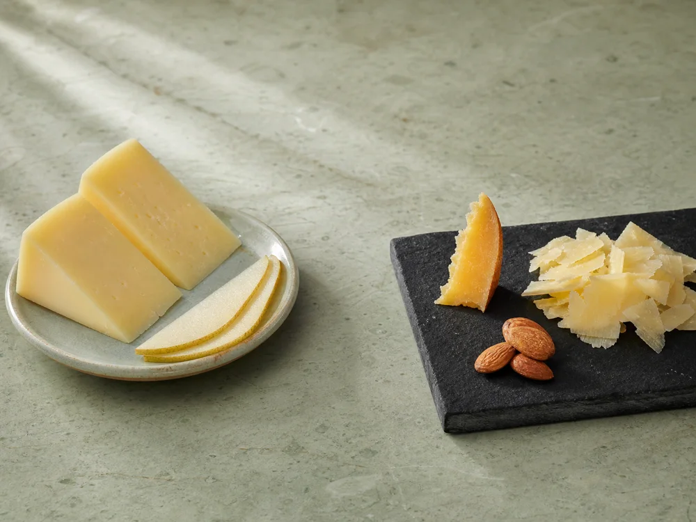 Thick Semicurado Mahón with pear beside shaved Curado and almonds - Mahón | KnowTheCheese