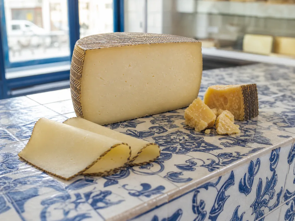 Pale Semicurado Manchego slices, a firm Curado half-wheel, and dry crystalline Viejo chunks - Manchego pairing | KnowTheCheese