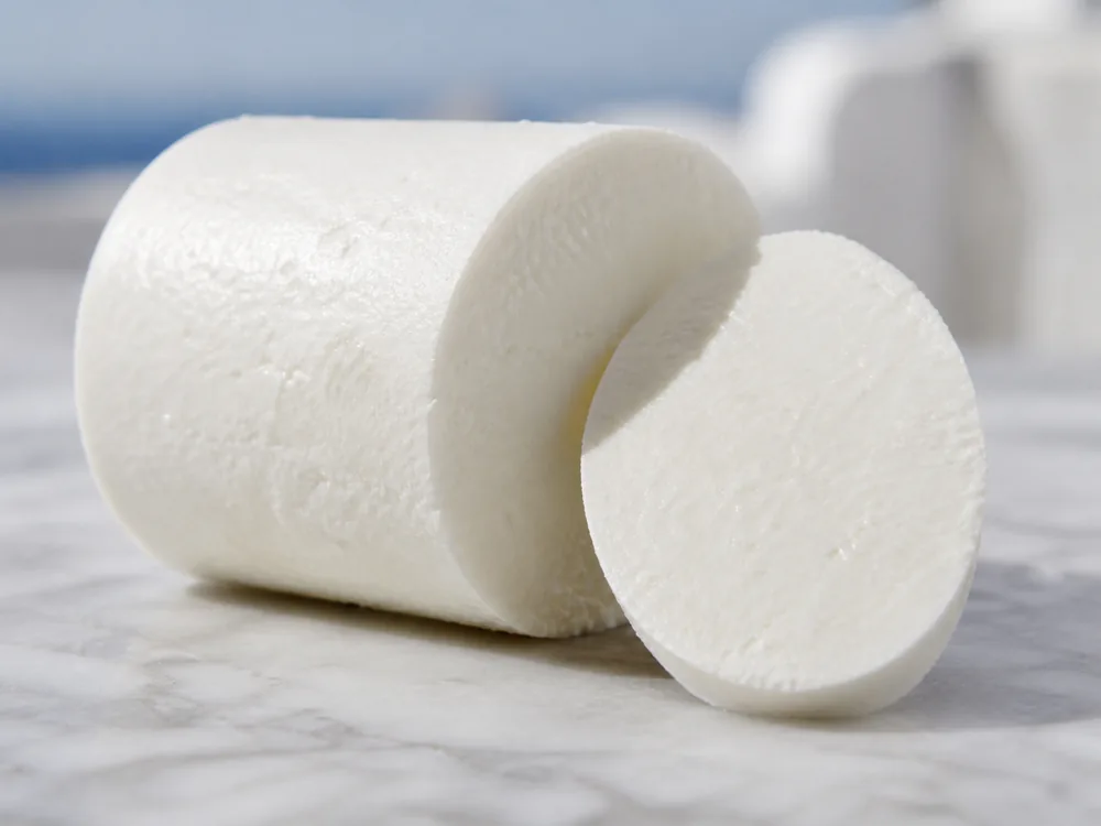 Cylindrical Manouri loaf cut to show its moist white fine-curd paste - Manouri | KnowTheCheese