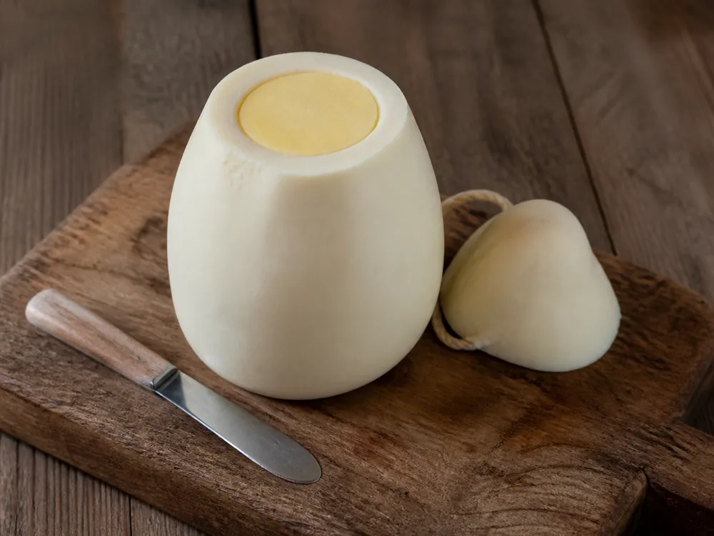 A Manteca with its top sliced off, showing the butter core level inside the cheese shell - Manteca | KnowTheCheese