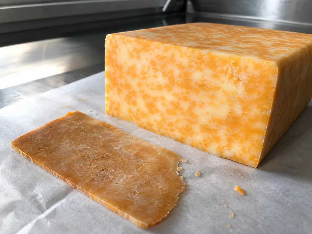 Fresh Marble Cheddar interior beside a trimmed dry outer slice - Marble Cheddar | KnowTheCheese