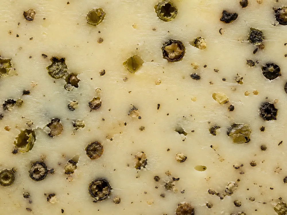 Cracked green and black peppercorns inside Marco Polo cheese - Marco Polo | KnowTheCheese