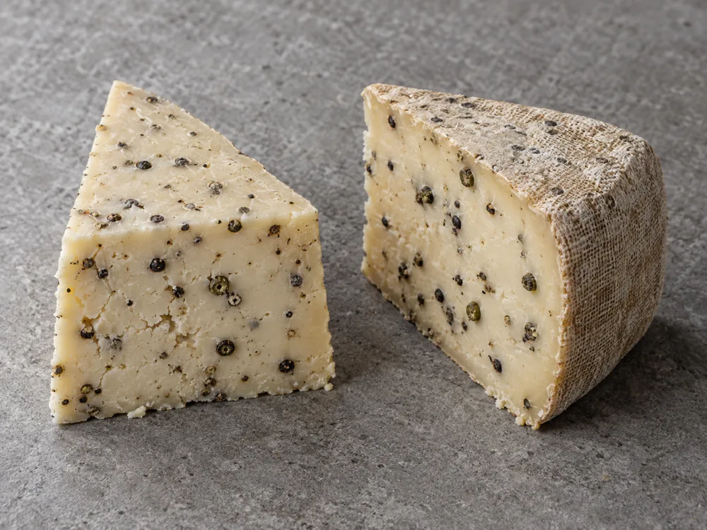 Standard wedge beside a cloth-wrapped wedge of peppercorn cheese - Marco Polo | KnowTheCheese