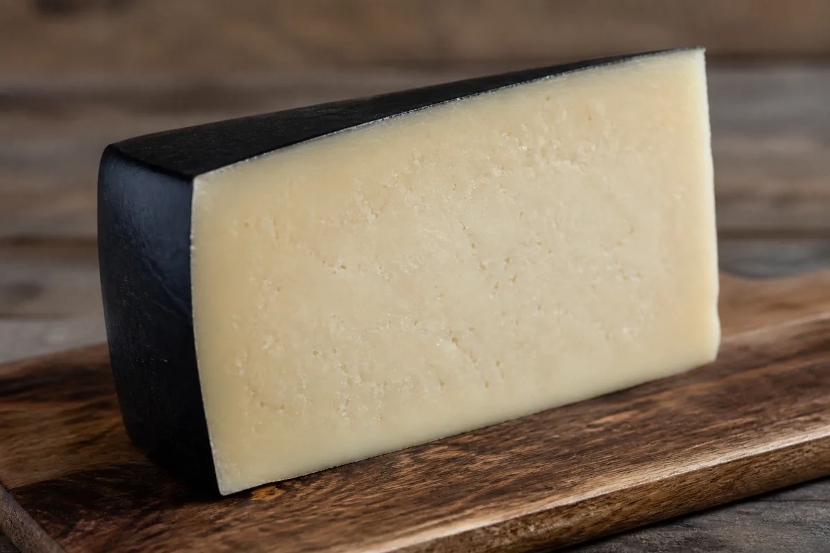 A wedge of firm ivory cheese edged with smooth black wax - Midnight Moon | KnowTheCheese