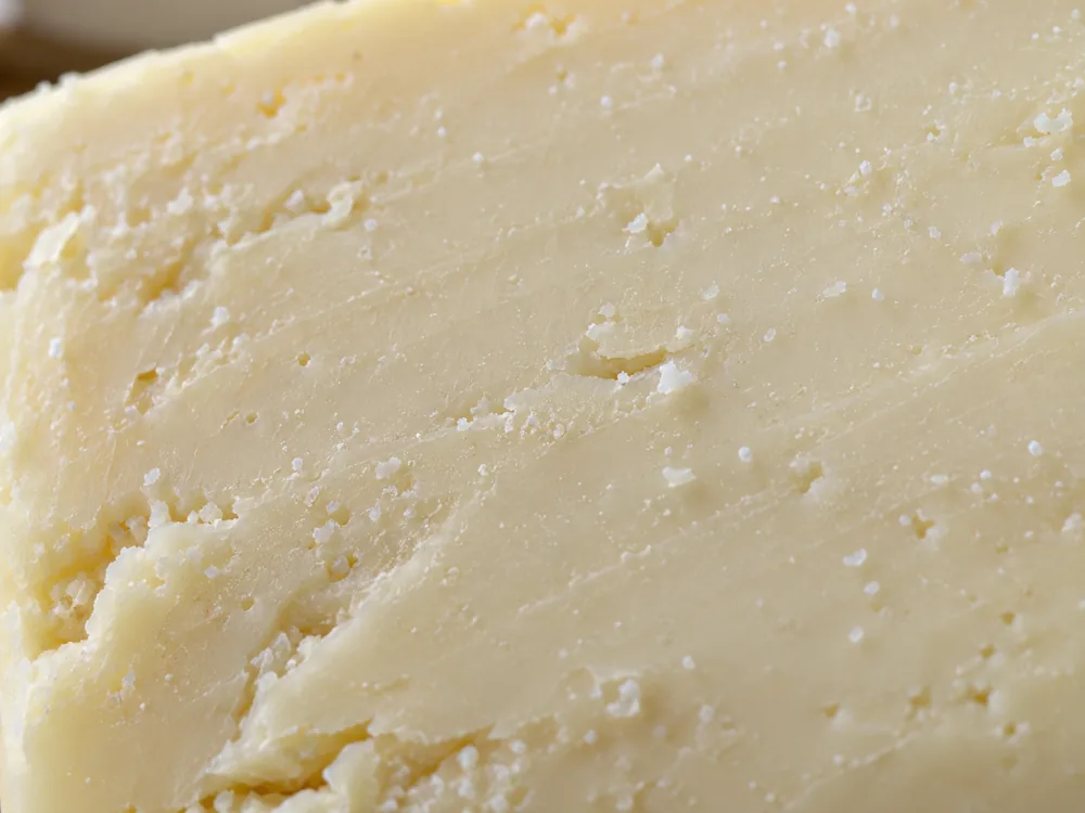 Close cut face of a dense ivory cheese with small white crystal specks - Midnight Moon | KnowTheCheese