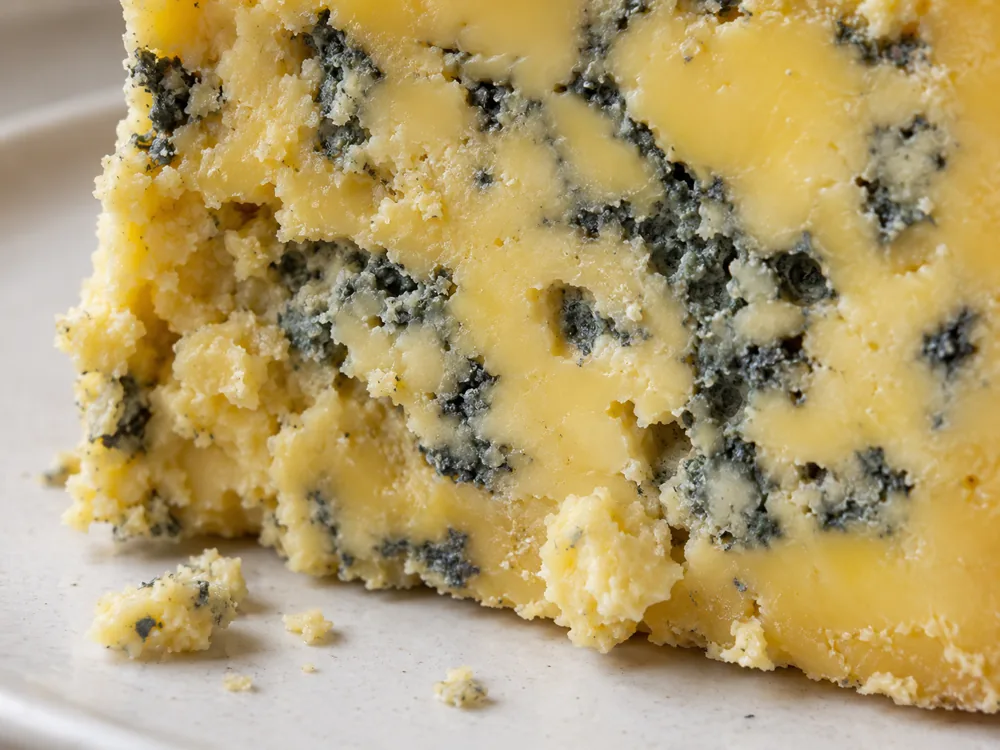 Close view of creamy yellow blue cheese with blue-grey veins and a crumbling edge - Milawa Aged Blue | KnowTheCheese