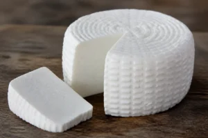 A moist white cylinder of fresh Minas cheese with one slice cut away - Minas cheese | KnowTheCheese