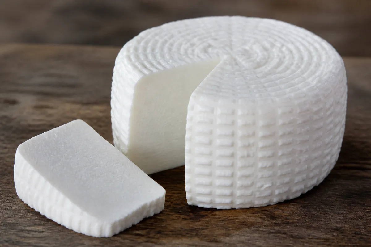 A moist white cylinder of fresh Minas cheese with one slice cut away - Minas cheese | KnowTheCheese