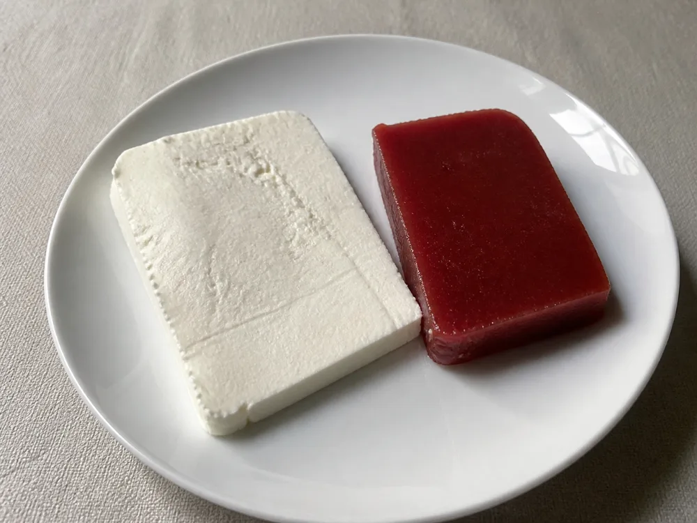 A slice of white fresh cheese beside a thick slab of dark red guava paste - Minas cheese | KnowTheCheese