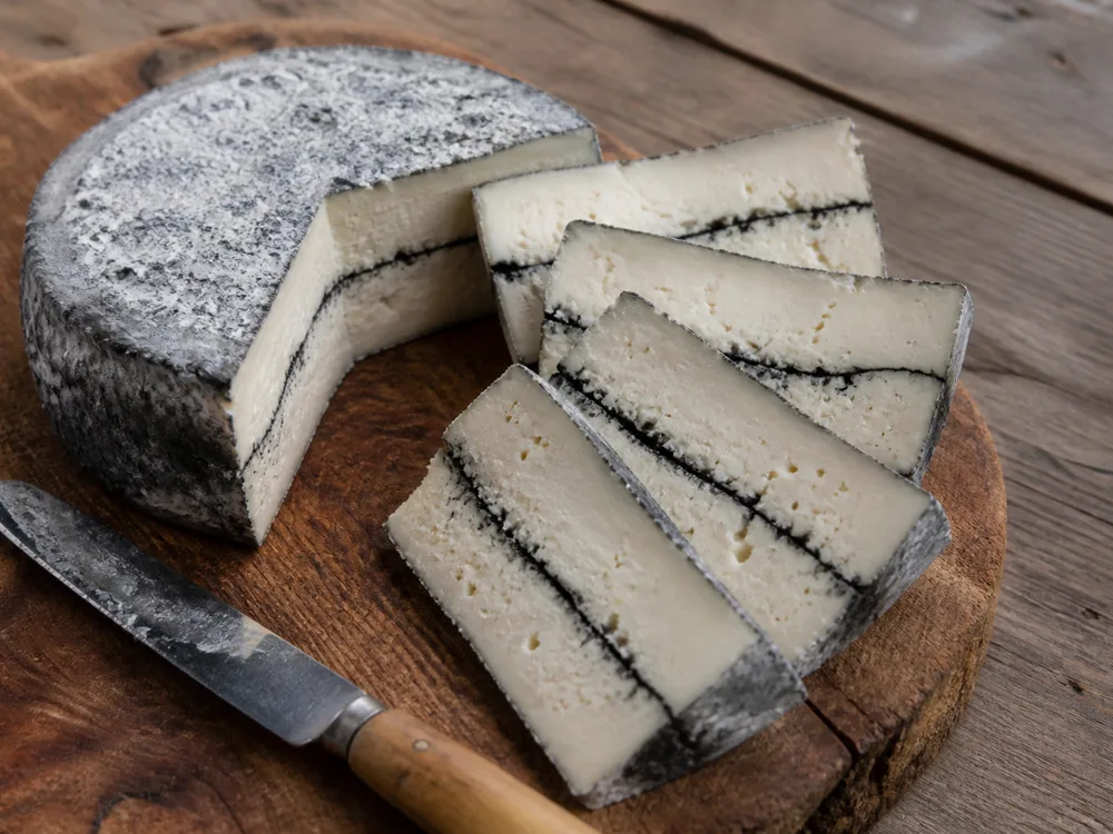 Slices of a layered cheese fanned out, each carrying both layers and the ash line - Mobay | KnowTheCheese