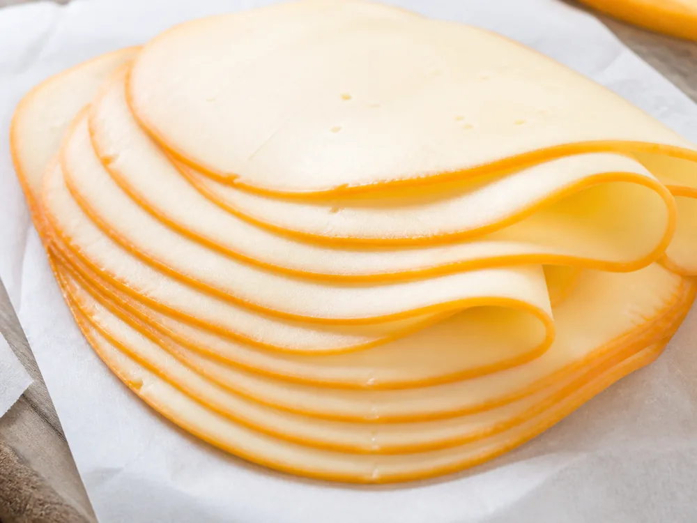 Muenster slices showing orange edge and pale paste - Muenster Cheese | KnowTheCheese