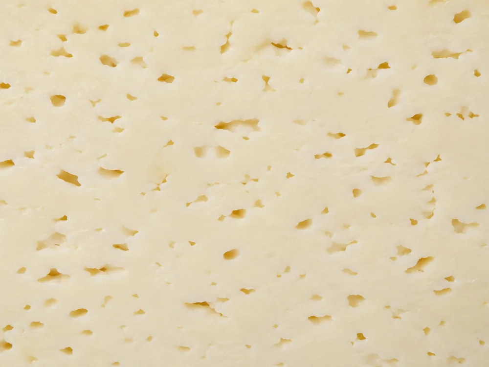 Macro of pale Oltermanni paste showing small irregular openings - Oltermanni | KnowTheCheese