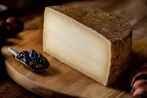 Wedge of Ossau-Iraty with firm ivory paste and brown rind - Ossau-Iraty cheese | KnowTheCheese