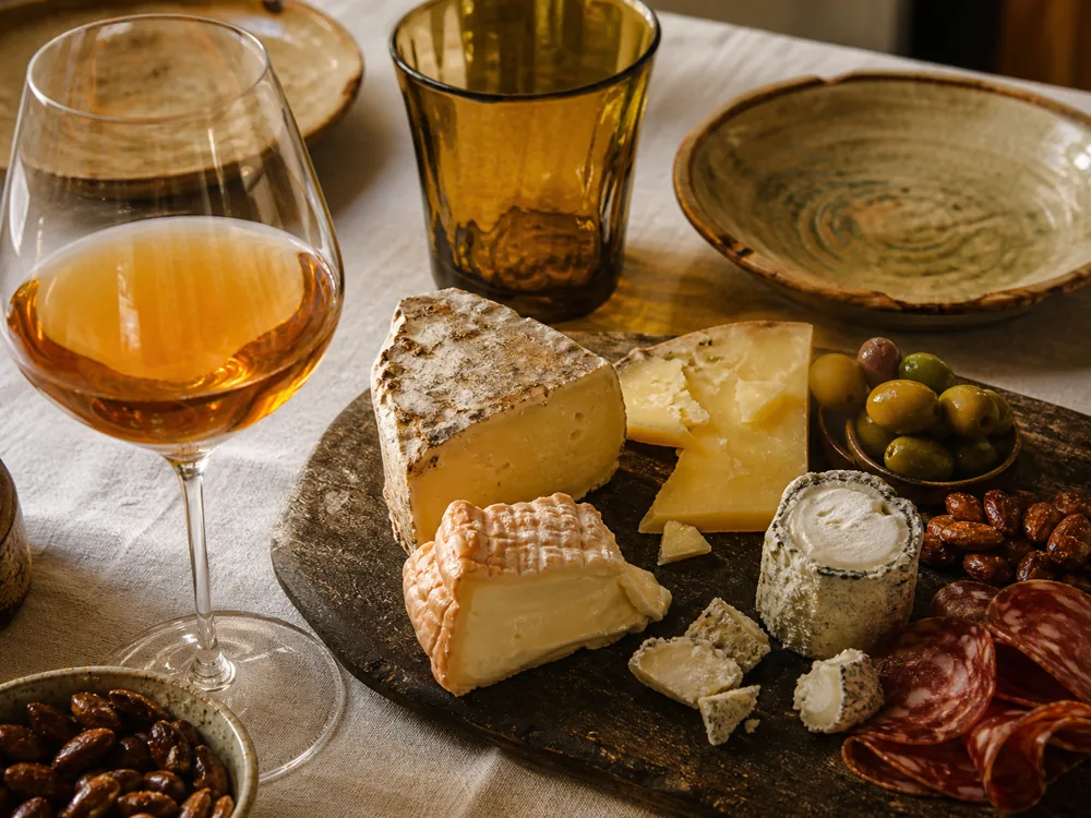 Orange wine with alpine, goat, and washed-rind cheeses on a charcuterie board - orange wine cheese pairing | KnowTheCheese
