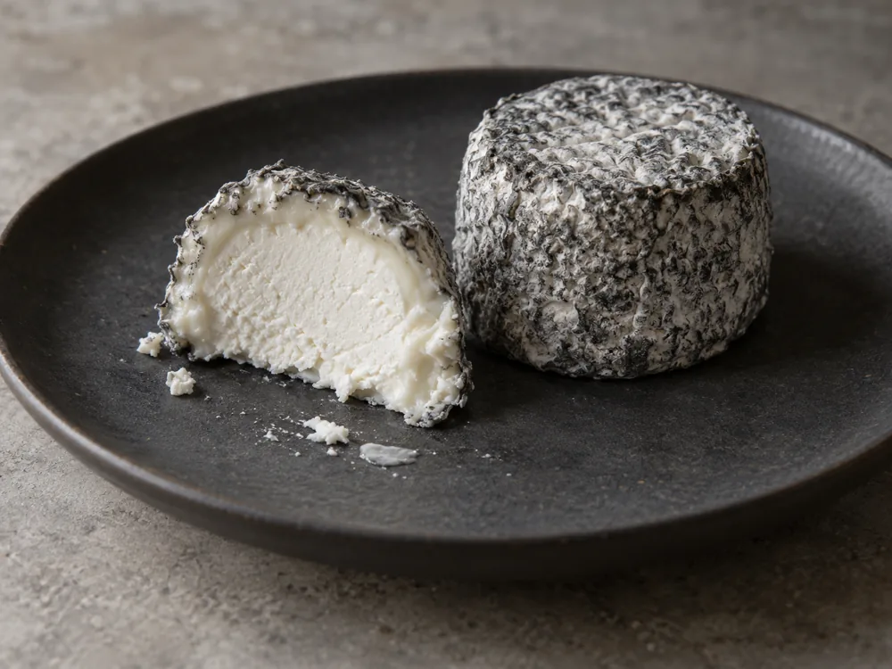 Ash-coated goat cheese cut open to show white paste | KnowTheCheese