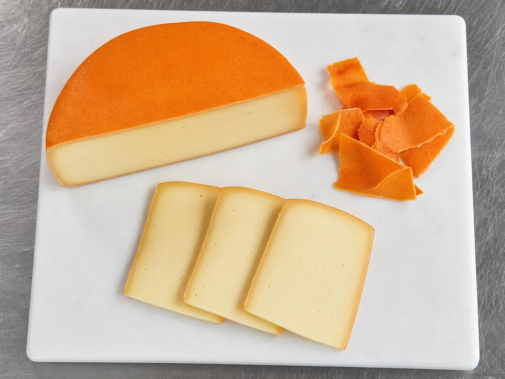 Orange coating trimmed from Port Salut before slicing - Port Salut | KnowTheCheese