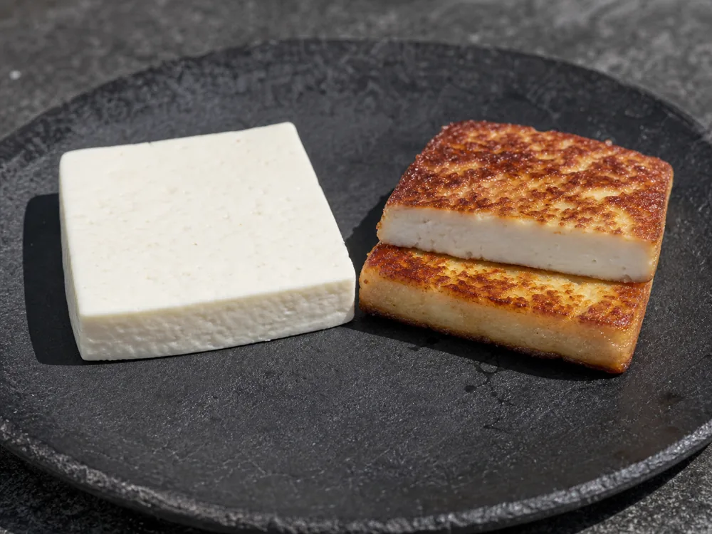 Raw Queso de Freir beside a browned slice with a firm white center